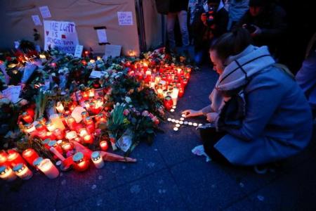 A woman places lit candles at the Christmas market in Berlin, Germany, December 20, 2016, where a truck ploughed into the crowd on Monday.           REUTERS/Fabrizio Bensch