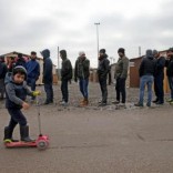 On the eve of International Migrants Day by United Nations, a Kurdish child from Iraq plays with a trotinette as migrants queue for food at a camp for migrants in Grande Synthe, France December 17, 2016. REUTERS/Pascal Rossignol