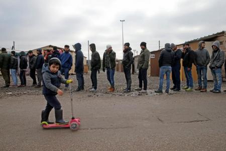 On the eve of International Migrants Day by United Nations, a Kurdish child from Iraq plays with a trotinette as migrants queue for food at a camp for migrants in Grande Synthe, France December 17, 2016. REUTERS/Pascal Rossignol