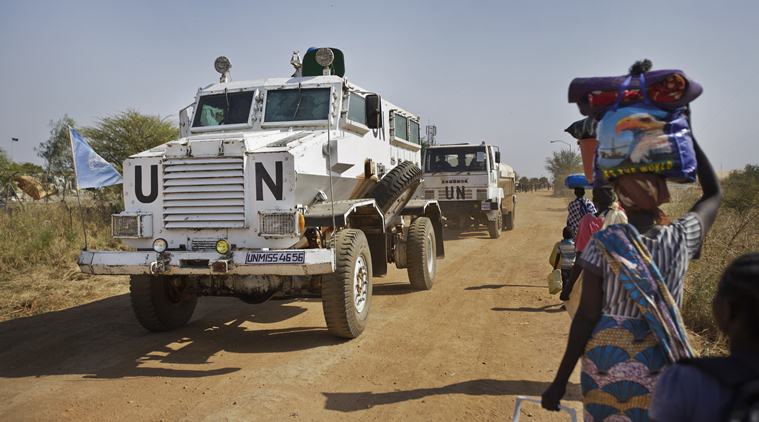 FILE - In this Monday, Dec. 30, 2013 file photo, a United Nations armored vehicle passes displaced people walking towards the U.N. camp in Malakal, South Sudan.  Minister of Cabinet Affairs Martin Lomuro said Saturday, Nov. 26, 2016, that the government has accepted to have with "no conditions" an increased peacekeeping force as mandated by the U.N. Security Council in August. (AP Photo/Ben Curtis, File)