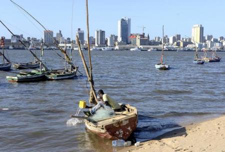 A fisherman cleans his boat beneath Maputo's skyline, in this picture taken August 15, 2015.  REUTERS/Grant Lee Neuenburg