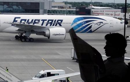 A passenger reads a newspaper at a departure hall of London's Heathrow terminal as an EgyptAir plane taxis on the tarmac of the airport May 20, 2016.  REUTERS/Yannis Behrakis
