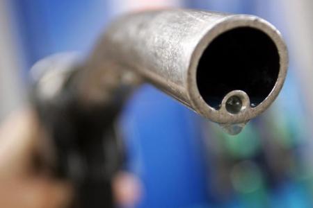 A motorist holds a fuel pump at a Gulf petrol station in London April 18, 2006.  REUTERS/Luke MacGregor/File Photo