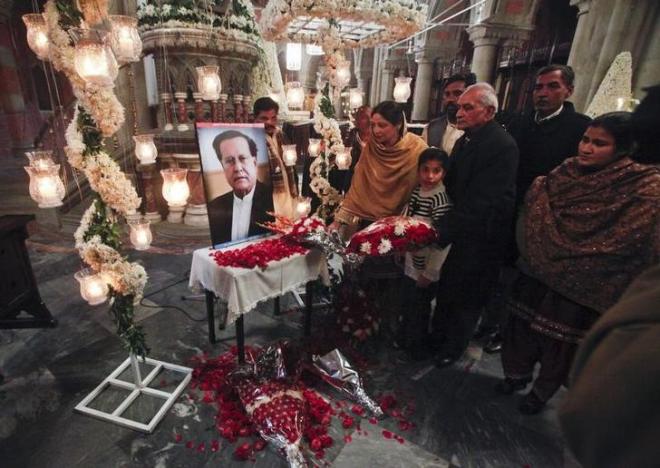 Pakistani Christians place flowers at a portrait of the assassinated Governor of Punjab Salman Taseer after a Sunday service at the Cathedral Church of the Resurrection in Lahore January 9, 2011. REUTERS/Mohsin Raza/File Photo