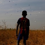 A boy watches sacks of food drop to the ground during a United Nations World Food Programme (WFP) airdrop close to Rubkuai village in Unity State, northern South Sudan, February 18, 2017. Picture taken February 18, 2017. REUTERS/Siegfried Modola