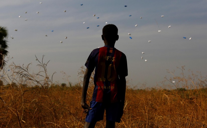 A boy watches sacks of food drop to the ground during a United Nations World Food Programme (WFP) airdrop close to Rubkuai village in Unity State, northern South Sudan, February 18, 2017. Picture taken February 18, 2017. REUTERS/Siegfried Modola