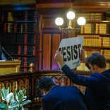 An environmental activist holds a banner reading "resist" while attending a speech by Myron Ebell (L), who leads U.S. President Donald Trump's Environmental Protection Agency's transition team, at the Solvay library in Brussels, Belgium February 1, 2017. REUTERS/Yves Herman