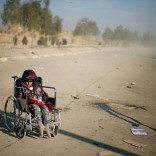 A disabled Iraqi girl who flees her home waits in a street for a truck to carry her to a safe place, as Iraqi forces battle with Islamic State militants, in western Mosul, Iraq March 7, 2017. REUTERS/Suhaib Salem