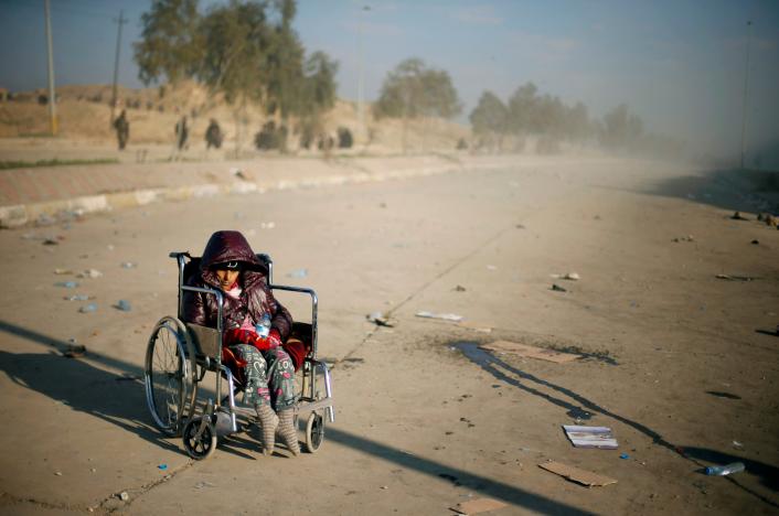 A disabled Iraqi girl who flees her home waits in a street for a truck to carry her to a safe place, as Iraqi forces battle with Islamic State militants, in western Mosul, Iraq March 7, 2017. REUTERS/Suhaib Salem