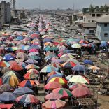 Traders sell their goods beneath large parasols at the Mile One open market in Port Harcourt, Nigeria, on Tuesday, Jan. 12, 2016. With his security forces engaged in fighting Boko Haram's Islamist insurgency in the north, President Muhammadu Buhari can't afford renewed rebellion in the delta. Photographer: George Osodi/Bloomberg