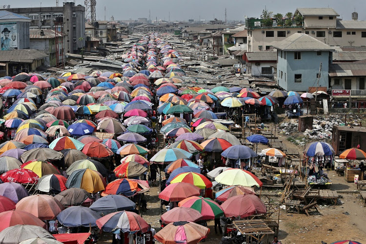 Traders sell their goods beneath large parasols at the Mile One open market in Port Harcourt, Nigeria, on Tuesday, Jan. 12, 2016. With his security forces engaged in fighting Boko Haram's Islamist insurgency in the north, President Muhammadu Buhari can't afford renewed rebellion in the delta. Photographer: George Osodi/Bloomberg
