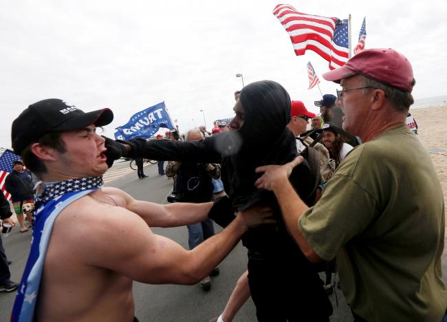A pro-Trump rally participant is punched in the face by an anti-Trump protester as the two sides clash at a Pro-Trump rally in Huntington Beach, California, U.S., March 25, 2017.    REUTERS/Patrick T. Fallon