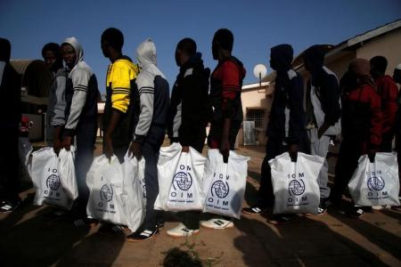 Gambian migrants who voluntarily returned from Libya stand in line with plastic bag from the International Organization for Migration (IOM) as they wait for registration at the airport in Banjul, Gambia April 4, 2017. REUTERS/Luc Gnago