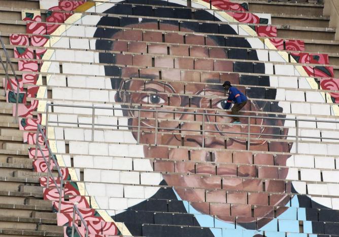 A worker puts final touches on a picture of Zimbabwean President Robert Mugabe at a rally to mark the country's 37th independence anniversary in Harare,  Zimbabwe, April 18, 2017.  REUTERS/Philimon Bulawayo