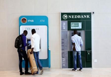 Customers queue to draw money from an ATM outside a branch of South Africa's Nedbank (R) and First National Bank (FNB) at a mall in Midrand outside Johanneburg, South Africa, April 28, 2016.REUTERS/Siphiwe Sibeko