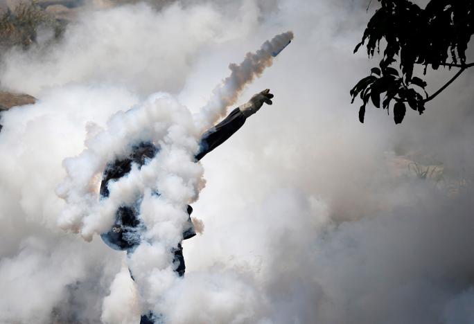 A demonstrator throws back a tear gas grenade while clashing with riot police during the so-called "mother of all marches" against Venezuela's President Nicolas Maduro in Caracas, Venezuela April 19, 2017. REUTERS/Carlos Garcia Rawlins