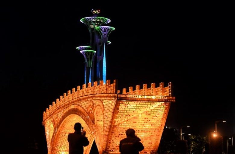 People take pictures in front of a "Golden Bridge on Silk Road" installation, set up ahead of the Belt and Road Forum, outside the National Convention Centre in Beijing, China May 11, 2017. Picture taken May 11, 2017.    REUTERS/Stringer