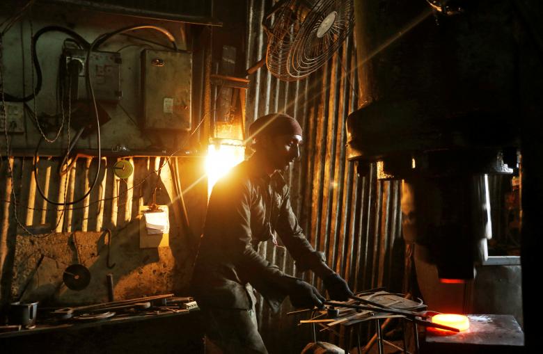 A worker operates a hydraulic press machine at a workshop manufacturing flanges for automobiles in Mumbai, India, May 29, 2017. REUTERS/Shailesh Andrade