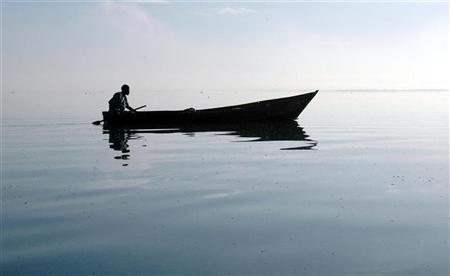 A Ugandan fisherman rows back to his nets at dawn on Uganda's Lake Victoria, March 21,2006.   REUTERS/Euan Denholm