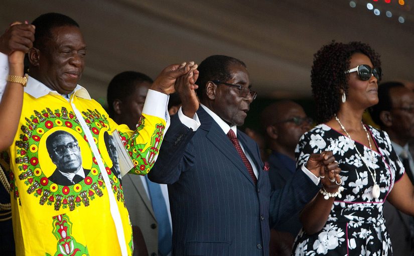 Zimbabwean President Robert Mugabe (C) holds hands with Vice President Emmerson Mnangagwa (L) and First Lady Grace Mugabe (R) during celebrations marking his birthday at the Great Zimbabwe monument in Masvingo on February 27, 2016. / AFP / JEKESAI NJIKIZANA        (Photo credit should read JEKESAI NJIKIZANA/AFP/Getty Images)