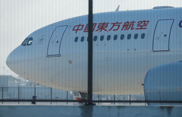 A man stands alongside the damaged engine of a China Eastern Airlines Airbus A330 aircraft on the tarmac at Sydney International Airport in Australia, June 12, 2017, after it made an emergency landing with a damaged engine.     REUTERS/Jason Reed