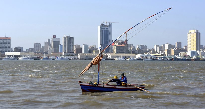 Traditional fishing boats sail as Mozambique's tuna fleet sits in dock beneath Maputo's skyline, in this picture taken August 15, 2015. Mozambique, one of the world's poorest countries, discovered the reserves off its coast between 2010-2013, offering an opportunity to transform the former Portuguese colony which was ravaged by a 16-year civil war that ended in 1992. Recent signs of reckless government spending and an uptick in political violence have raised concerns that Mozambique could be the latest African country to suffer the resource "curse," in which an influx of petro-dollars suffocates the rest of the economy, encourages corruption and stirs unrest.  Picture taken August 15, 2015.  REUTERS/Grant Lee Neuenburg - RTX1TA2Z