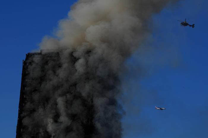 A helicopter and an airplane are seen as flames and smoke billow while firefighters deal with a serious fire in a tower block at Latimer Road in West London, Britain June 14, 2017. REUTERS/Toby Melville