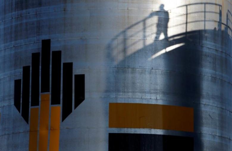 FILE PHOTO: The shadow of a worker is seen besdide the logo of the Rosneft oil company at an oil field in Russia, August 4, 2016. REUTERS/Sergei Karpukhin/File Photo