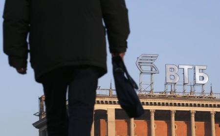 A pedestrian walks on a street, with the logo of VTB Bank displayed on the roof of a building, in Moscow, November 20, 2014.  REUTERS/Maxim Zmeyev