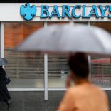 FILE PHOTO: Pedestrians shelter under umbrellas as they walk past a Barclays branch in central London May 8, 2014.  REUTERS/Stefan Wermuth/File Photo
