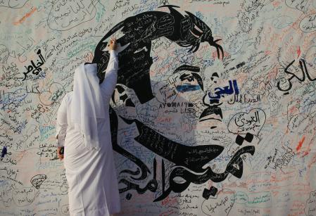 A man writes on a painting depicting Qatar’s Emir Sheikh Tamim Bin Hamad Al-Thani in Doha, Qatar, July 2, 2017. REUTERS/Naseem Zeitoon