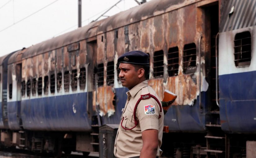 A security personnel member stands guard outside a burnt carriage of a train near a railway station in New Delhi, India, August 26, 2017. REUTERS/Adnan Abidi