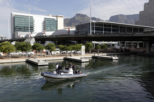 Police patrol a canal near the Cape Town International Convention Centre December 3, 2009. The final draw, involving the 32 teams that qualified for the 2010 Soccer World Cup, takes place on Friday evening at the convention centre and will see 1,000 police deployed to protect dignitaries. Soccer stars such as David Beckham are expected to attend.    REUTERS/Rogan Ward (SOUTH AFRICA SPORT SOCCER) - RTXREUC