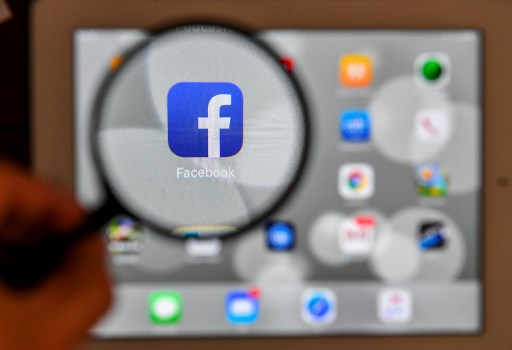A tablet screen displays the logo of the social networking site Facebook through a magnifying glass, in Bogota, on March 22, 2018.
A public apology by Facebook chief Mark Zuckerberg on March 22 failed to quell outrage over the hijacking of personal data from millions of people, as critics demanded the social media giant go much further to protect privacy. / AFP PHOTO / Luis ACOSTA