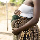 A pregnant African woman holding her stomach.